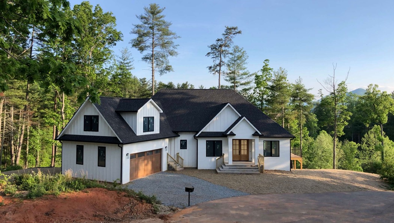 Completed custom home exterior with contrasting siding, stonework, and landscaped front yard