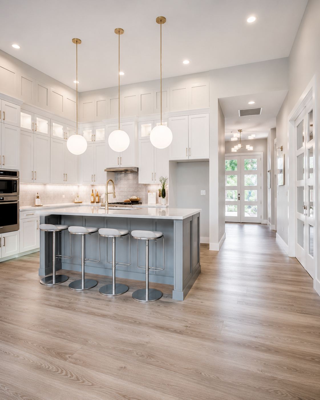 Custom white kitchen with gray island, globe pendant lights, and light wood flooring